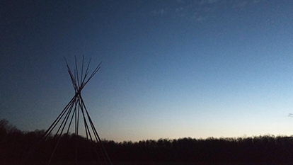 A tipi in the distance at sunset.
