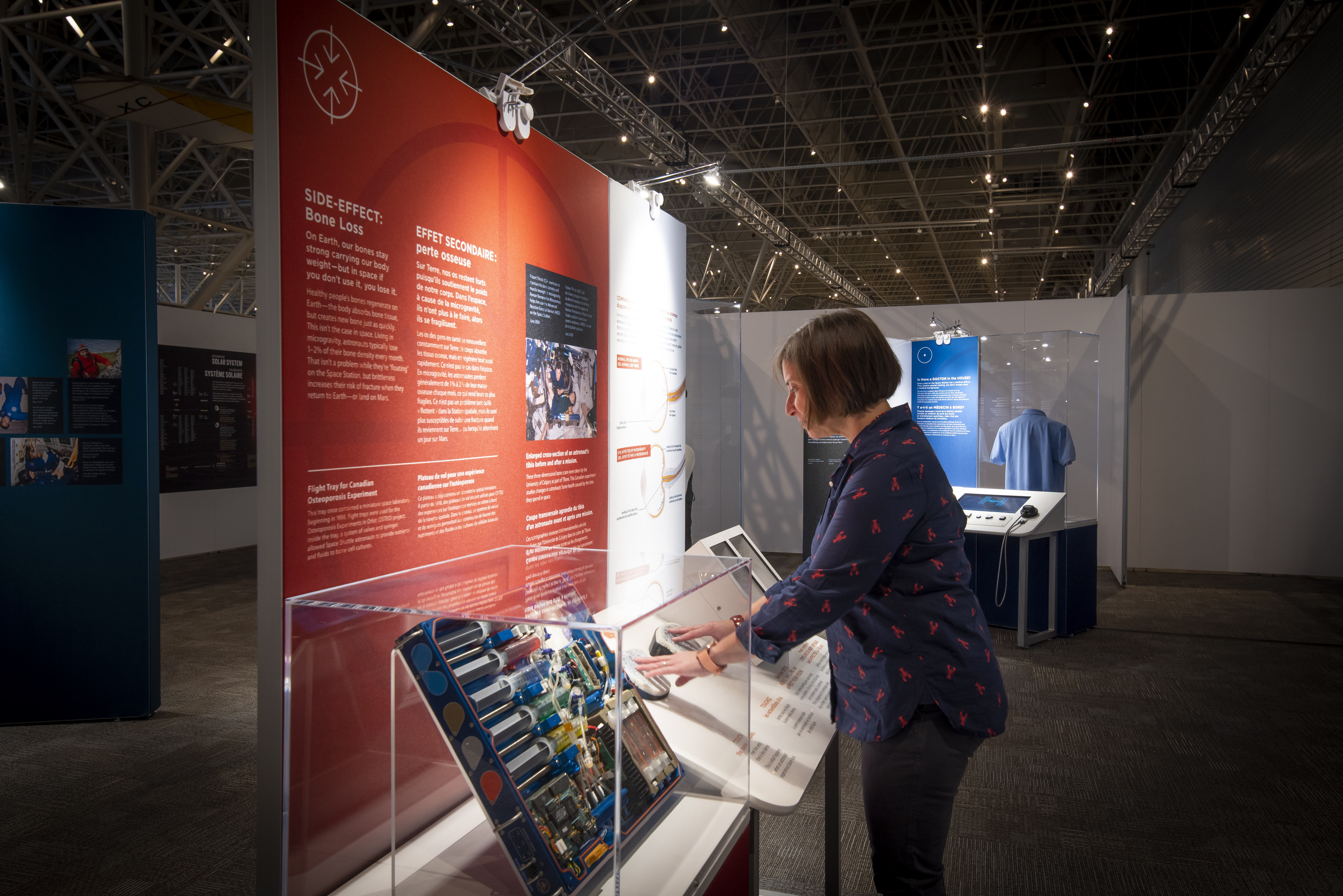 Une femme se trouve devant un panneau d’une exposition présentée au Musée de l’aviation et de l’espace du Canada.