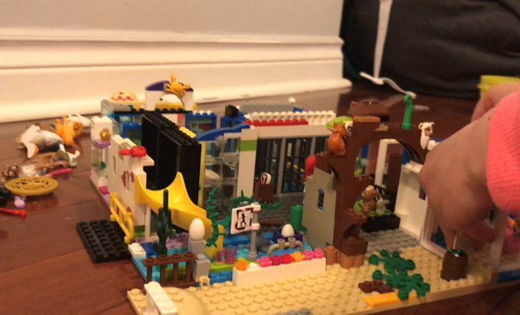 L’œuvre en LEGO® d’une enfant, intitulée « The Future of the Zoo » (L’avenir du zoo), est posée sur un plancher. On peut voir le bras de l’enfant.