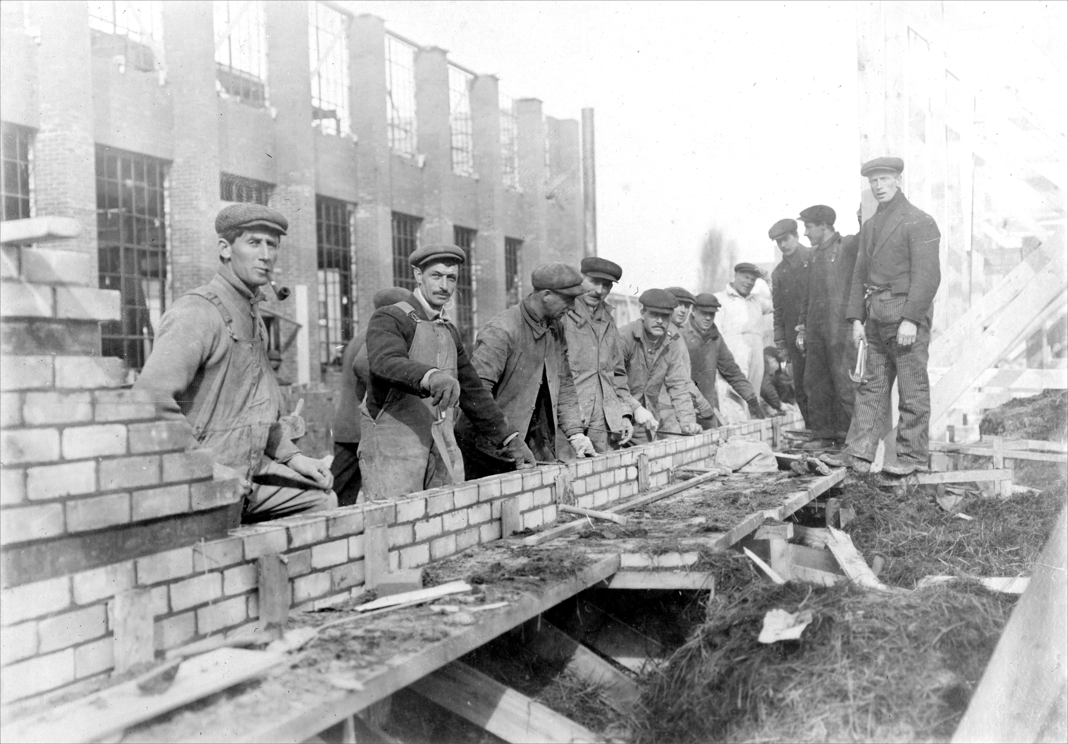 Workers laying bricks at the factory site, ca February 1917.