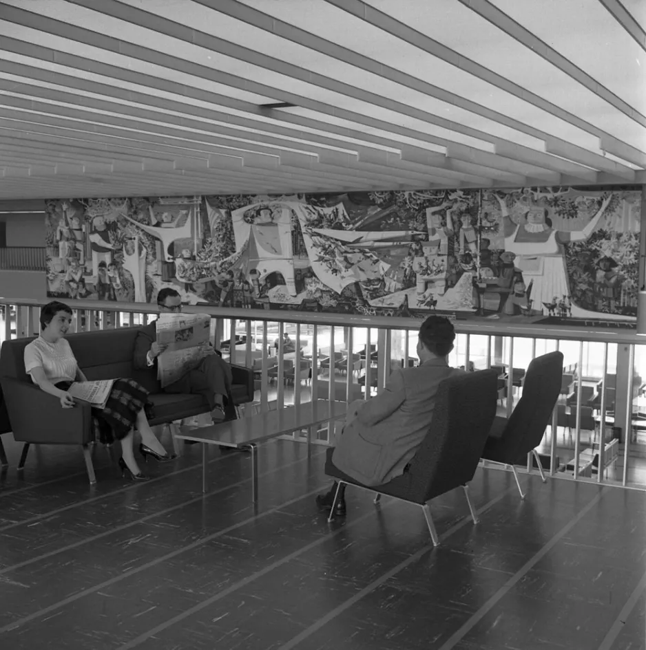 People waiting in the international lounge of the new terminal. Artist Ken Lochhead’s impressive mural is visible in the background.