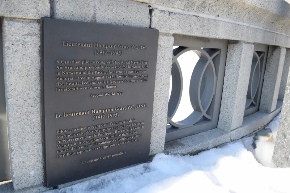 A plaque is attached to a concrete wall. It reads: “Lieutenant Hampton Gray, VC, DSC (1917-1945) A Canadian pilot serving with the Royal Navy’s Fleet Air Arm, and previously decorated for heroism, both in Norway and the Pacific, he earned a posthumous Victoria Cross in August 1945. Despite intense enemy fire, he attacked and sank a Japanese destroyer before his aircraft went down in flames. Second World War.”