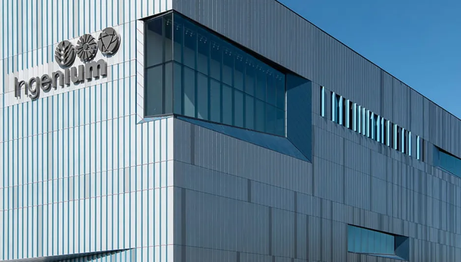Un grand bâtiment moderne sur fond de ciel bleu et dégagé. Le mot « Ingenium » en grandes lettres apparaît sur le devant de la façade bleu-gris du bâtiment.