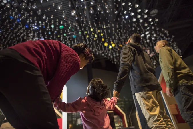 Une famille regarde une installation d'ampoules dans le musée