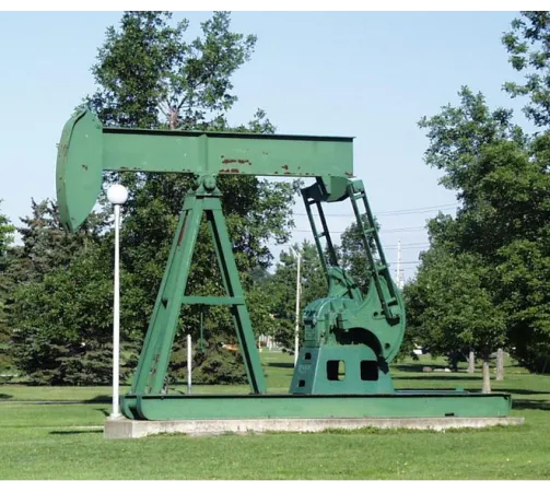 An oil pump jack in a green field.