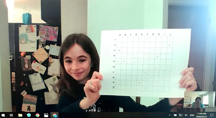 [Alt Text] Photo de l’écran d’un ordinateur durant un vidéoclavardage. À l’écran, une fille souriante exhibe une grille parsemée d’inscriptions colorées.
