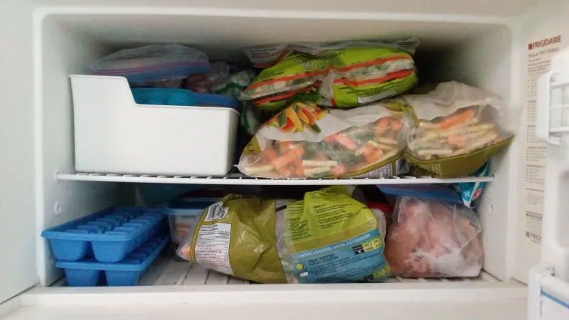 An open freezer filled with vegetables. 