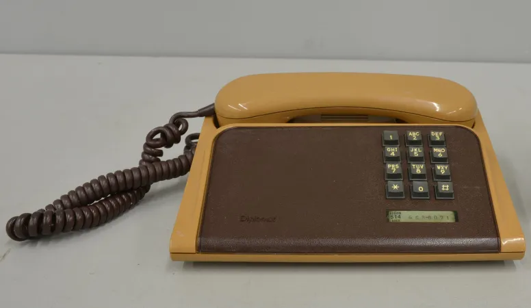 A brown desk phone with a matte keyboard plate, clean after treatment, sits on a grey background.