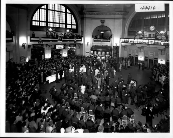 Image is a black–and-white photograph showing a crowd of returning service men at a train station. 