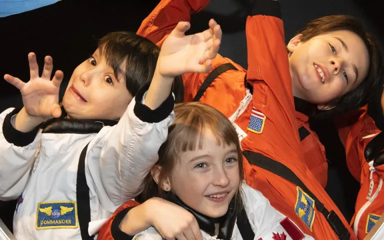 Four young children are dressed in astronaut suits