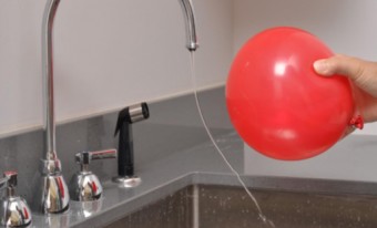 Un ballon est tenu près d'un évier avec de l'eau courante. Le jet d'eau s'incline vers le ballon.