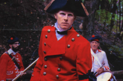 A young man poses as James Wolfe, dressed in historical dress including a red jacket and black hat.