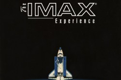 A white and blue space shuttle leaves the Earth’s atmosphere and is pointing upwards to the words “The IMAX Experience.”  The image background is black, the text is white, and we can see a blue ocean with some white clouds in the Earth at the bottom of the picture.