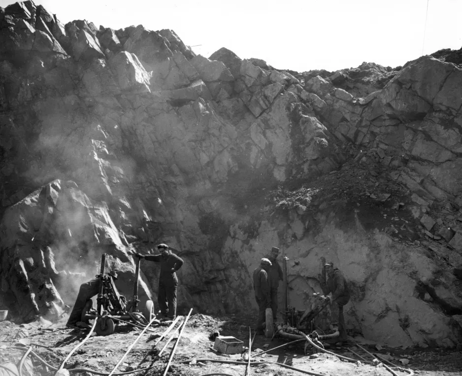 Photograph shows drillers at work on the face of an entire hill of iron ore, Bathurst, New Brunswick, 1943