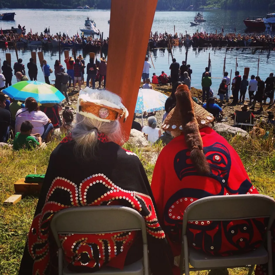 Two community elders sit and watch canoes land on the shore in Bella Bella during Qatuwas 2014