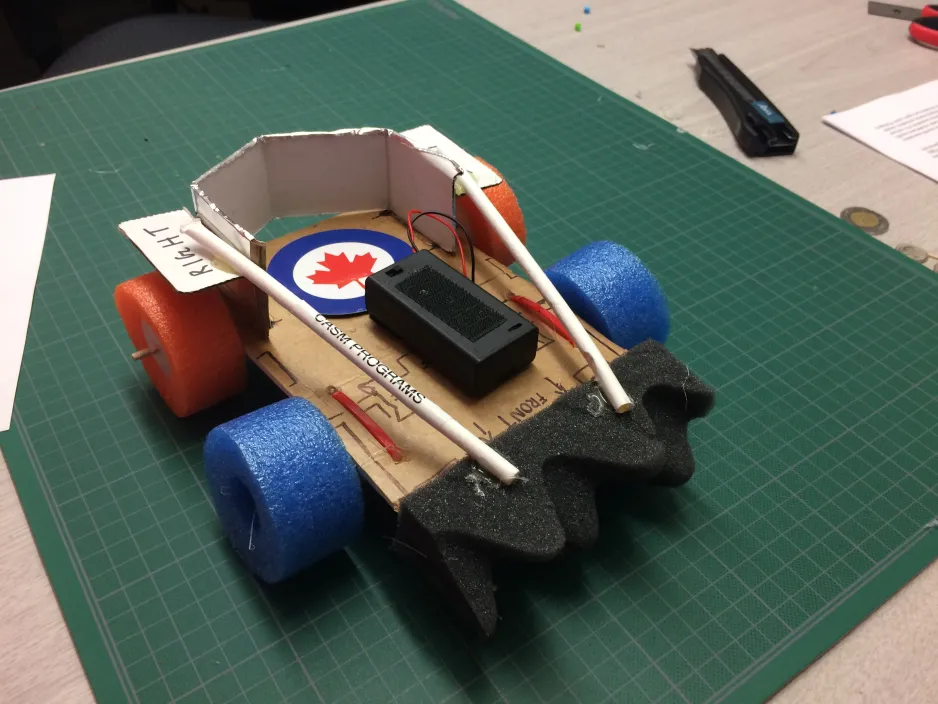 3.	A hand-crafted car with colourful foam wheels sits on a desk.