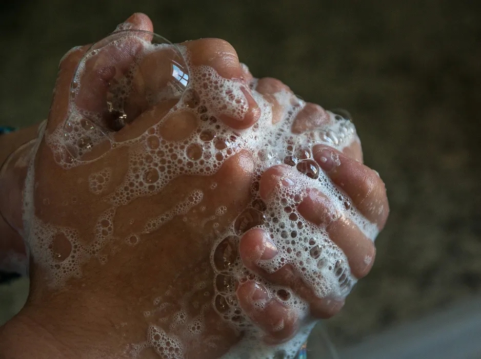 Gros plan sur une personne qui se lave les mains avec beaucoup de savon. 