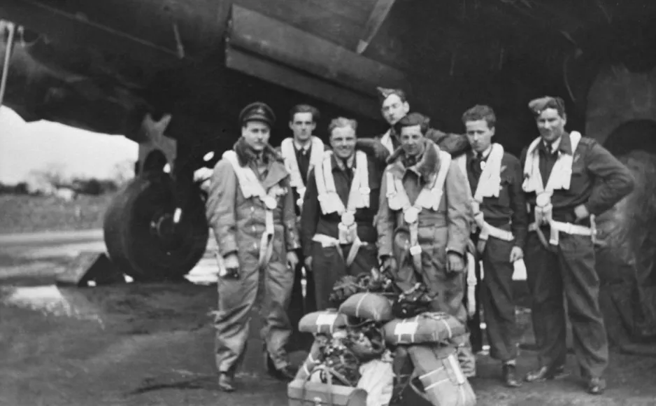 Une image en noir et blanc d’un équipage de vol composé d’hommes, vêtus de leur uniforme, debout devant un gros aéronef.