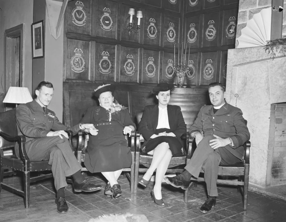 Une image en noir et blanc de deux hommes et de deux femmes assis et élégamment vêtus.