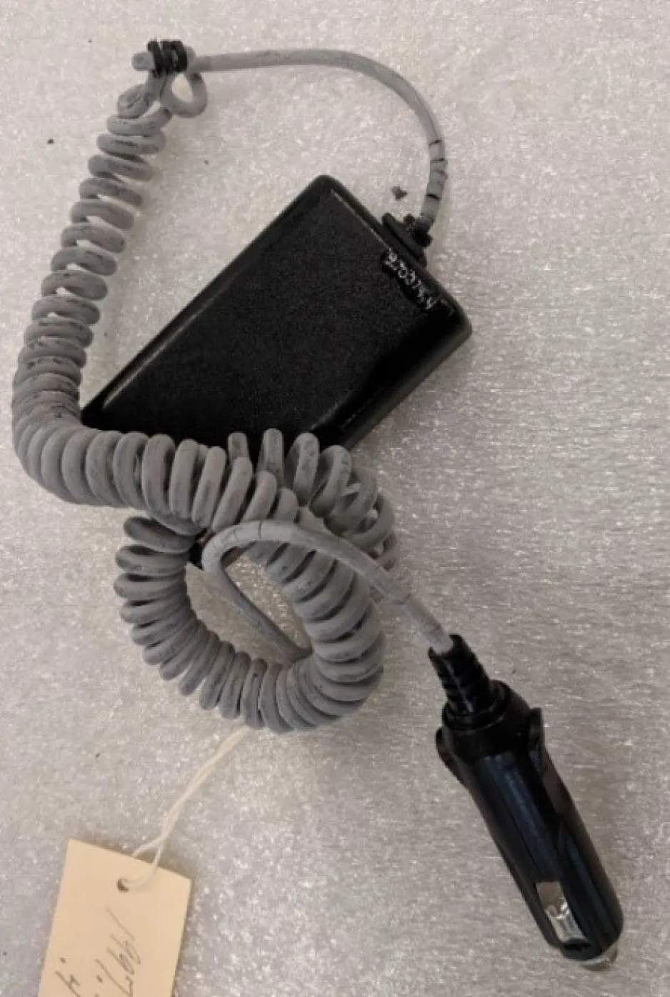 A grey and black cord sites on top of a grey table top.