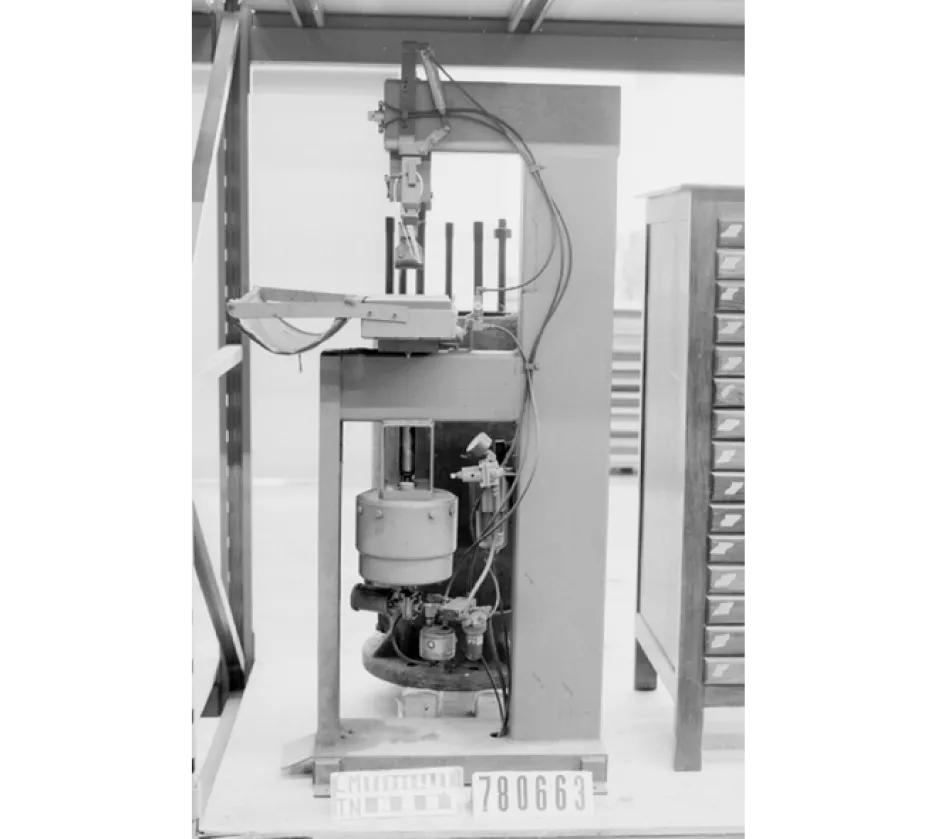 Photo en noir et blanc d’une petite machine, utilisée dans les années 1950 pour transformer des feuilles de métal.