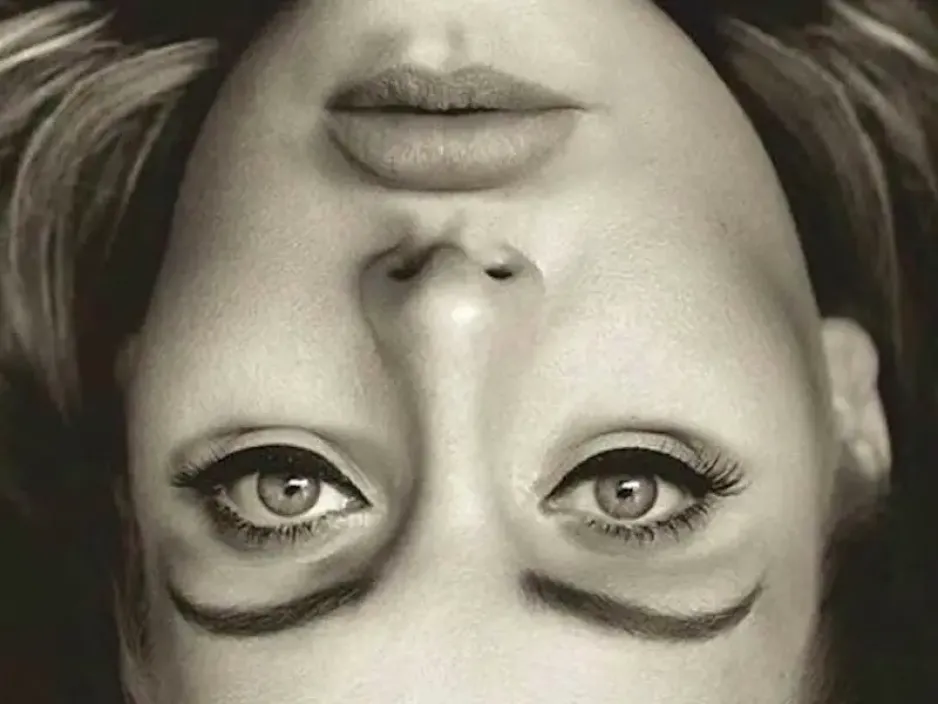 A black-and-white image shows a close-up of a woman’s face; the image appears to be flipped upside down. 