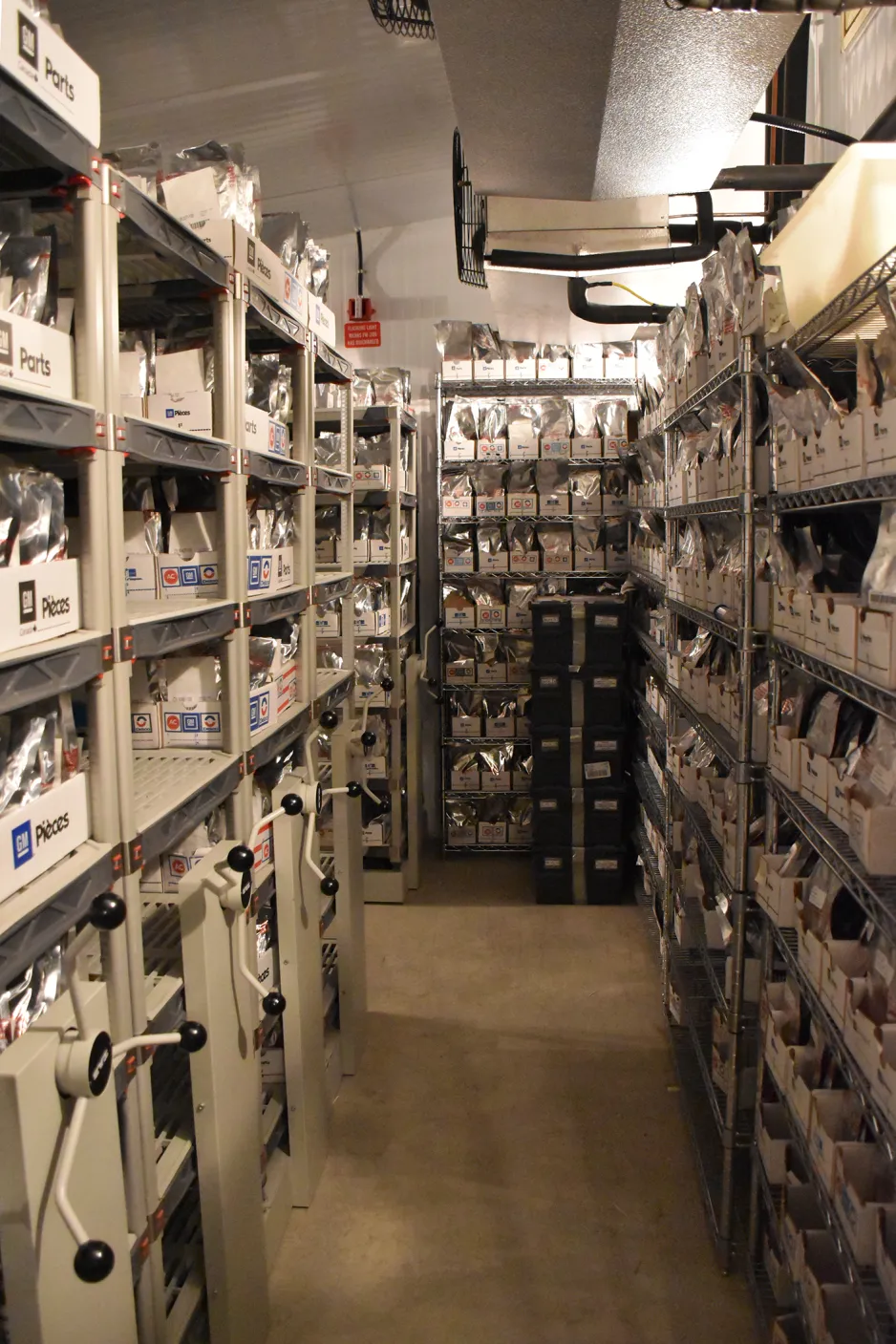 A view down a hallway lined with shelves. The shelves hold rows of boxes, filled with shiny silver pouches.