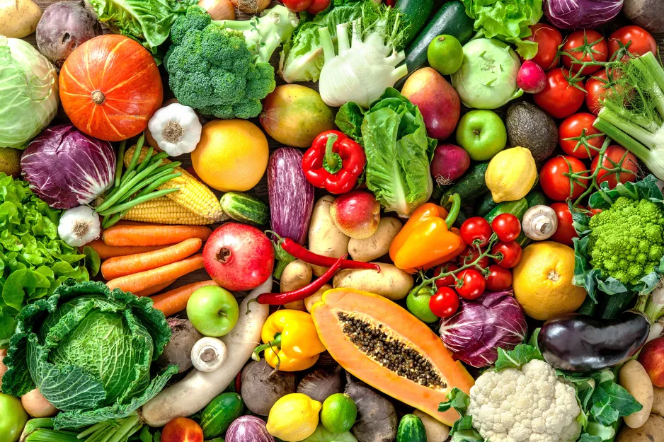 Colourful spread of fruit and vegetables, laid out on a table and shot from above.