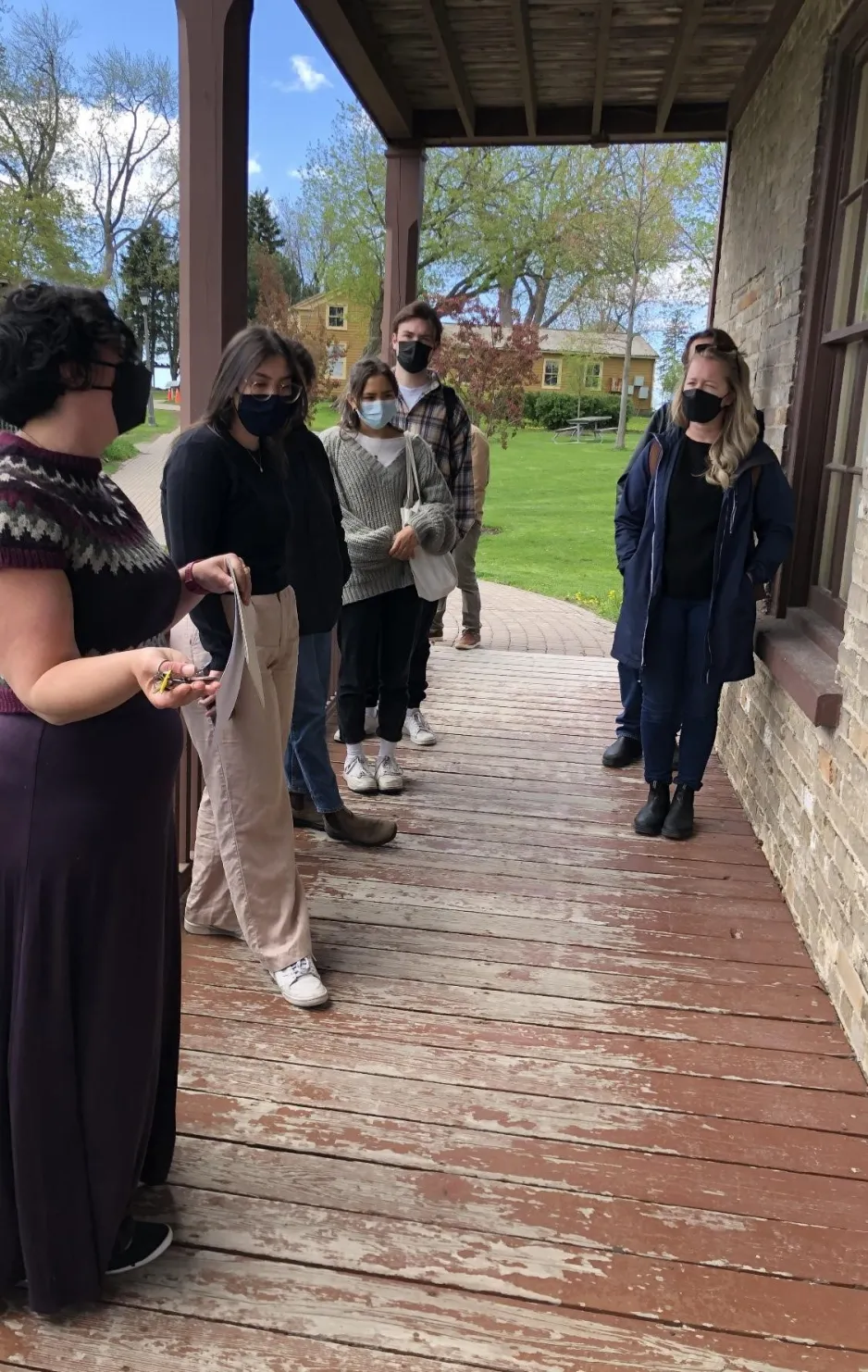 Photo de l’équipe du projet Contesting Closure du programme Jackman de chercheurs invités écoutant une guide parler de l’histoire d’Oshawa, lors d’une excursion au Musée d’Oshawa. 