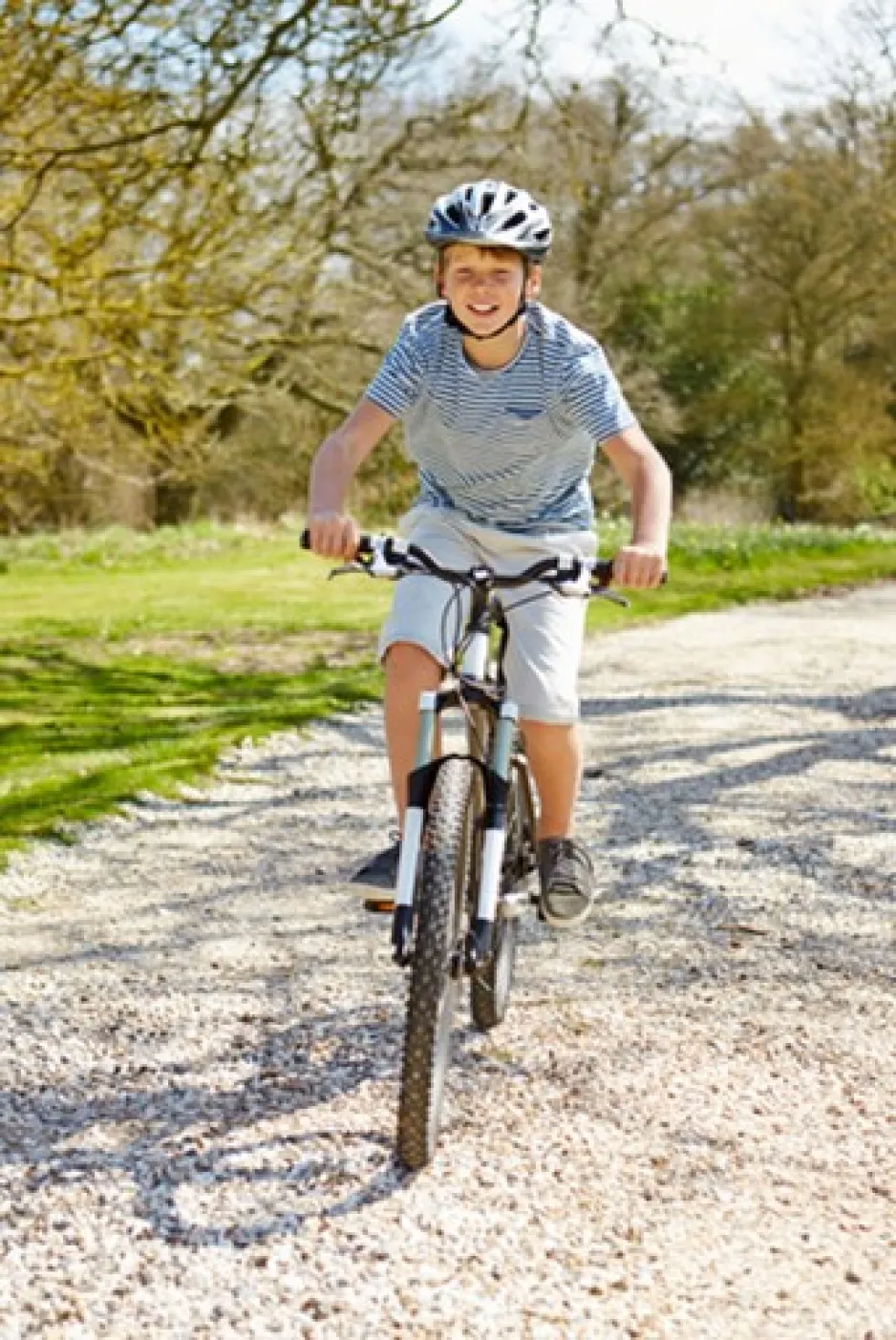 Un garçon portant un casque de protection fait du vélo. 