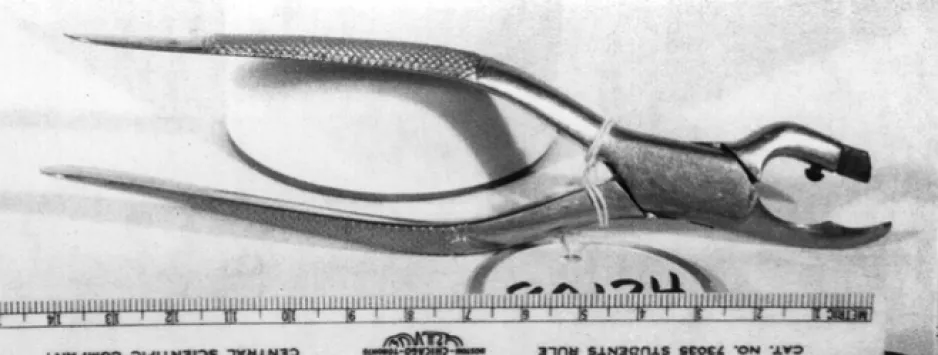 Un outil de métal, ressemblant à une paire de pinces, repose sur une surface pâle.