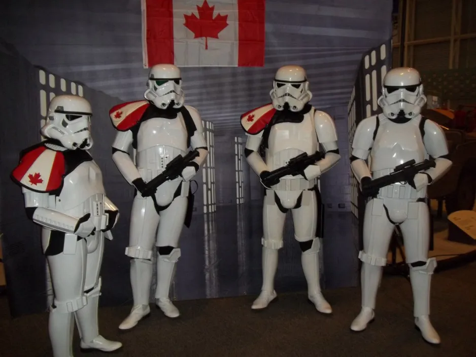 Quatre personnes en costumes de Storm Trooper avec des écussons du drapeau canadien sur l'épaule.