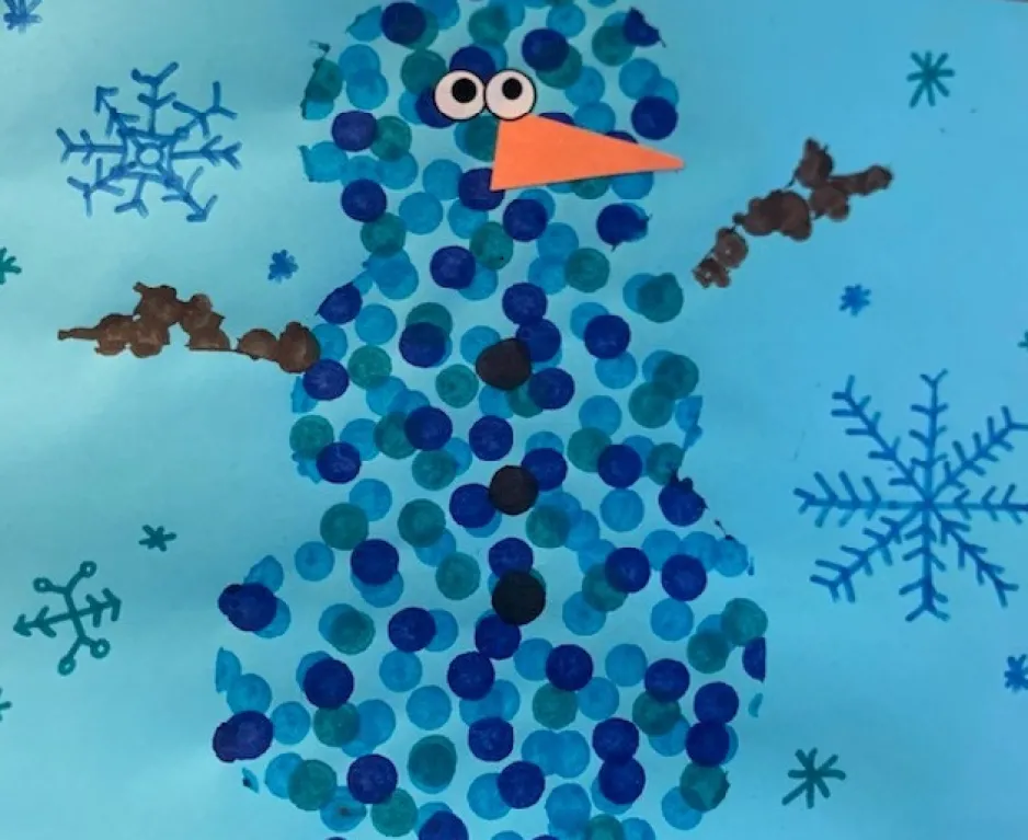 Un bricolage pour enfants représente un bonhomme de neige sur fond bleu.