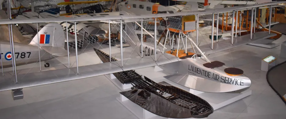 This image shows a large, silver-coloured boat aircraft; it is a bi-plane, meaning it has two sets of wings, layered top of one another, and there is space between the sets of wings created by vertical bars called struts.