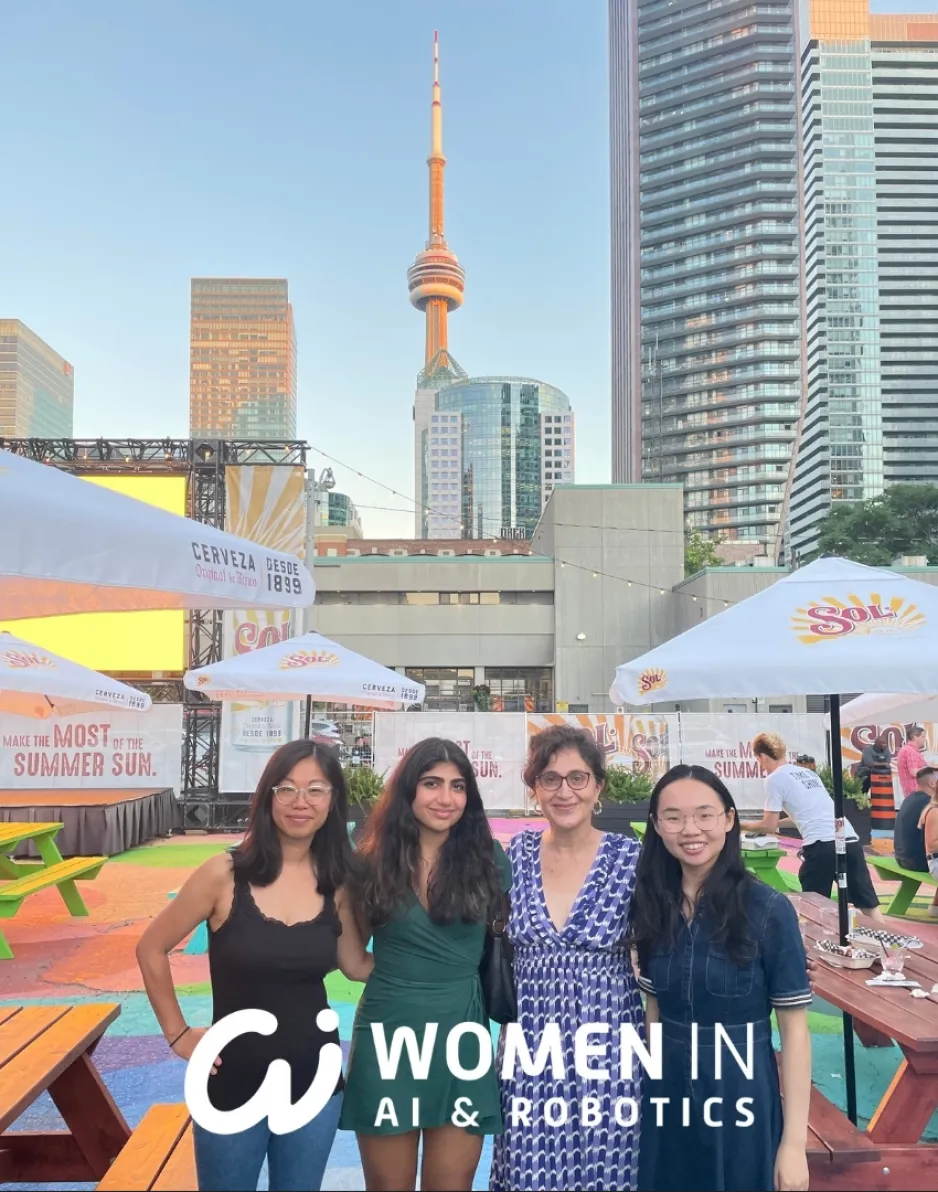Quatre femmes se tiennent debout sur une place entourée de parasols de patio. On aperçoit une scène à l'arrière-plan et la ville de Toronto, avec la tour du CN, à l'arrière-plan. 