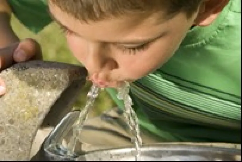 Gros plan d'un garçon buvant de l'eau à une fontaine.