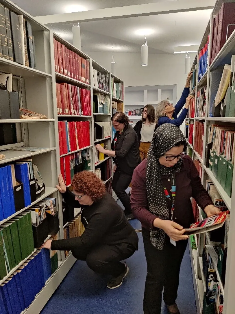 Une partie de l'équipe du personnel de la bibliothèque d'Ingenium devant les étagères de livres regardant des livres et des périodiques.