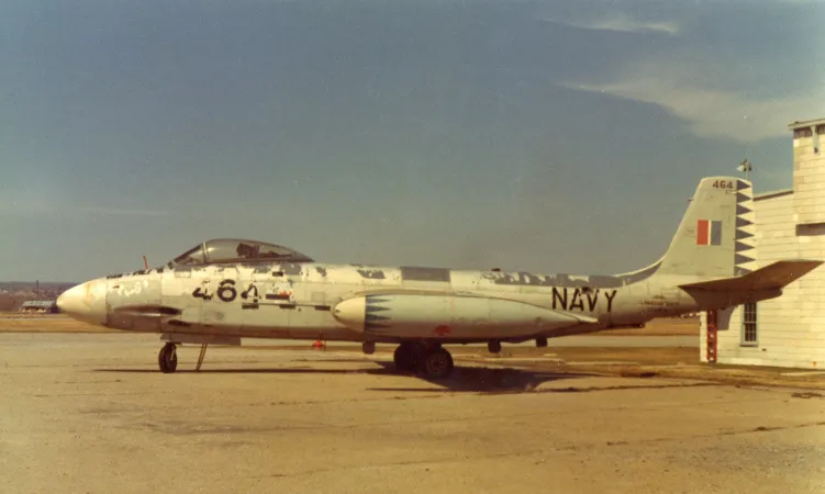 Left-side view of a jet airplane, sitting on a runway. Peeling paint is evident.
