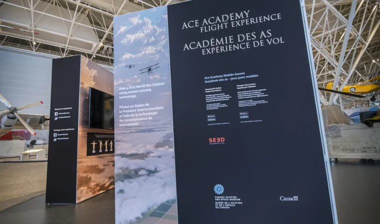 Un grand panneau d’exposition avec le titre « Académie des as, expérience de vol » et du texte en dessous.