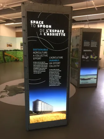 Un module d’exposition; on voit le titre de l’exposition, « De l’espace à l’assiette », et une image de silos, dans le bas.