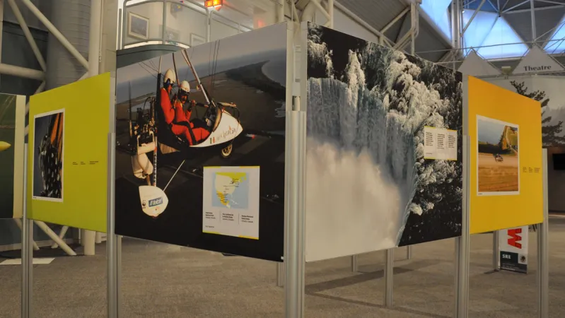 A close-up view of several exhibition panels with photographs of a two people in a small plane and a waterfall.