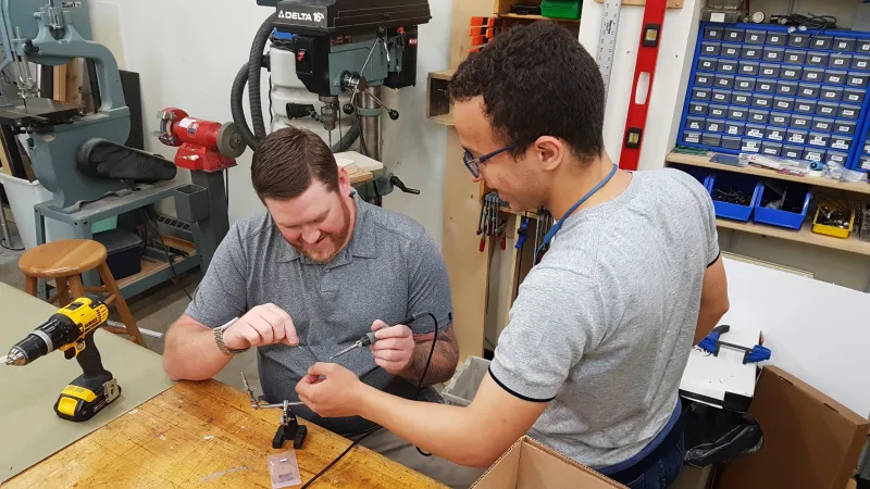 Jason helping Mohamed with soldering to a sensor