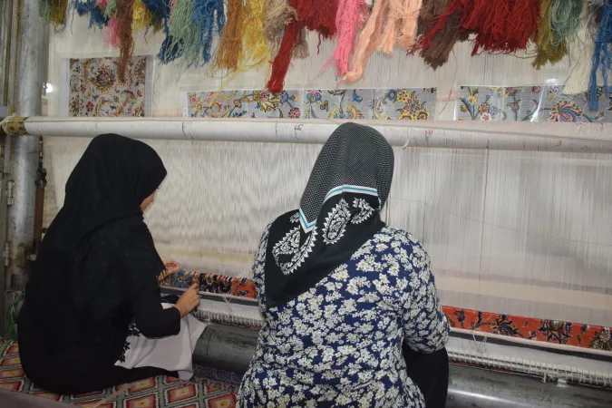 A mother and daughter weaving a carpet. 