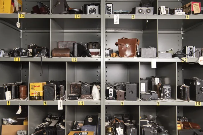 A full wall of cubby holes, each filled with camera equipment.