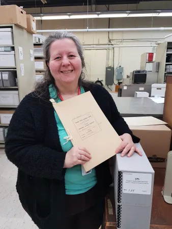 Photograph of archives clerk Sian Jones with a report from the Canada Pacific Steamships fonds