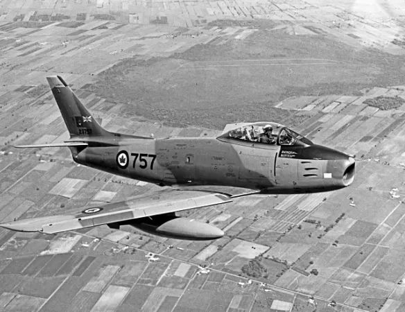 A Canadair Sabre 6 flying above a town