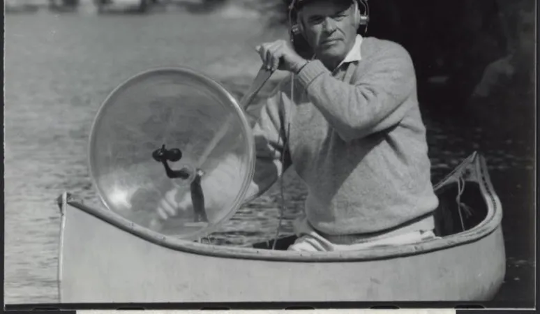 Dan Gibson, muni de son microphone parabolique stéréo, lors d’un enregistrement dans un canot au parc Algonquin (Ontario, Canada). Source : Bibliothèque et Archives Canada/e011163804