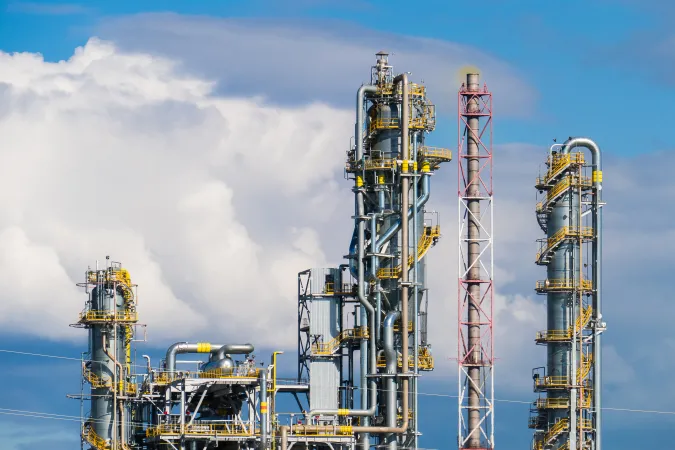 Des tours d’une usine de production d’engrais azoté ressortent contre un ciel bleu nuagé.