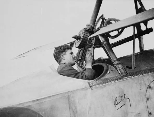 A black-and-white image of William Avery Bishop in the cockpit of a Nieuport aircraft, handling a machine gun. 