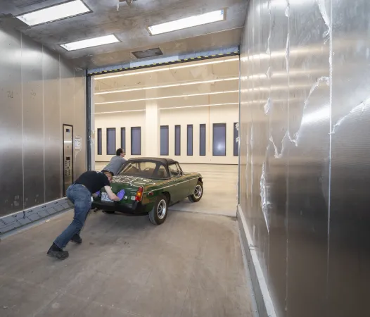 A green sports car is pushed off of the large freight elevator.